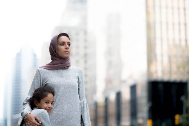 мусульманские мать и ребенок обнимаются в городе - migrants стоковые фото и изображения