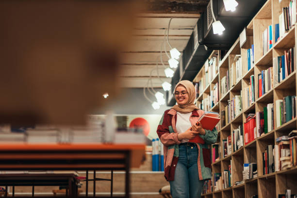 Muslim student carrying some books in library stock photo