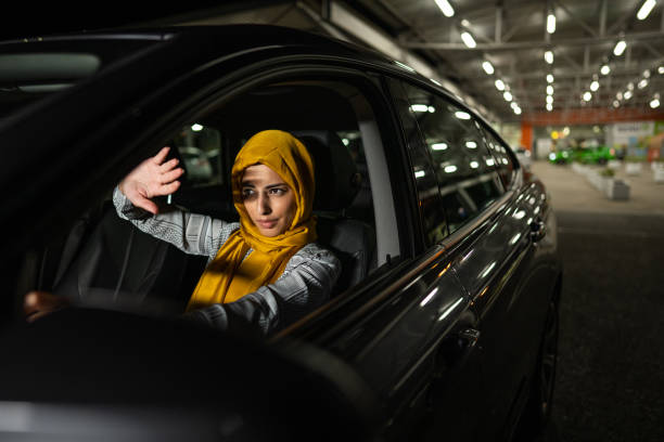 Muslim woman covering her eyes from strong light from another car at night stock photo