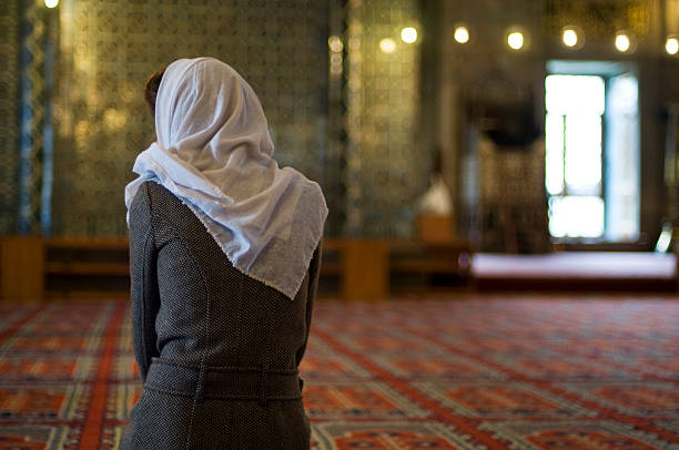 muslim woman is praying in the mosque stock photo