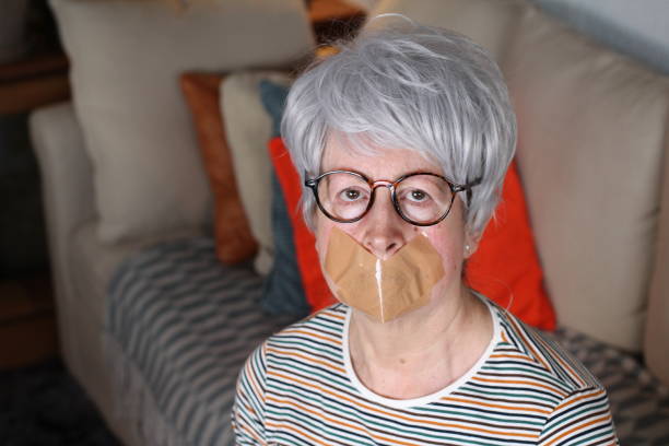 Muted senior woman at home Muted senior woman at home. human mouth gag adhesive tape women stock pictures, royalty-free photos & images
