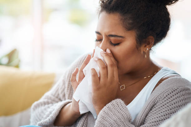 My day just keeps getting worse Cropped shot of a young woman blowing her nose with a tissue at home sneezing stock pictures, royalty-free photos & images