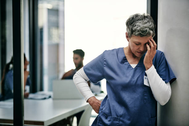 My job can be so stressful at times Shot of a mature female nurse suffering from a serious headache while working inside a hospital uncomfortable photos stock pictures, royalty-free photos & images
