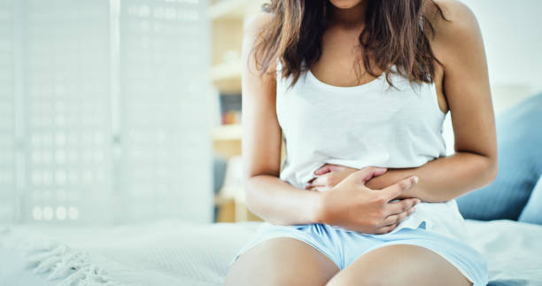 My stomach is in disarray Shot of an unrecognizable woman suffering from stomach cramps in her bedroom stomachache photos stock pictures, royalty-free photos & images