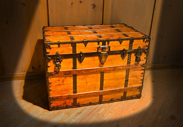 Mysterious old antique treasure chest in attic Old mysterious antique wood and metal locked pirate treasure chest in attic of old wooden house in a spotlight with heavy shadow. jewelry treasure chest gold crate stock pictures, royalty-free photos & images