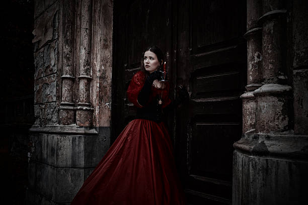 Mysterious woman in red Victorian dress with a candle stock photo