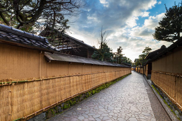 Nagamashi district or samurai district street over a dramatic sky showing the earthen walls, tsuchi-kabe, covered in winter with straw mats, Ishikawa prefecture, Japan. stock photo