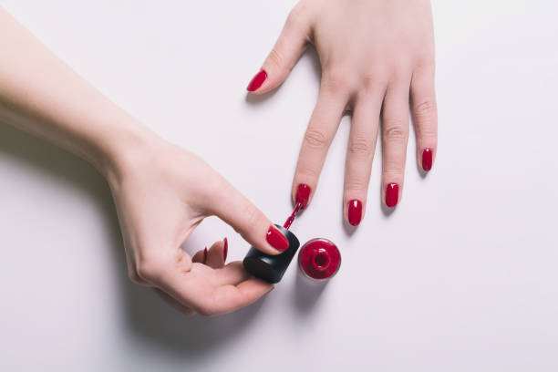 Nail polishing Woman polish her nails with red polish color on a white background. Above view enamel stock pictures, royalty-free photos & images
