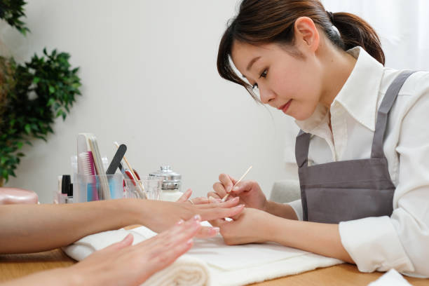 Nail stylist decorating fingernail Nail stylist putting decoration stone on fingernail nail salon stock pictures, royalty-free photos & images