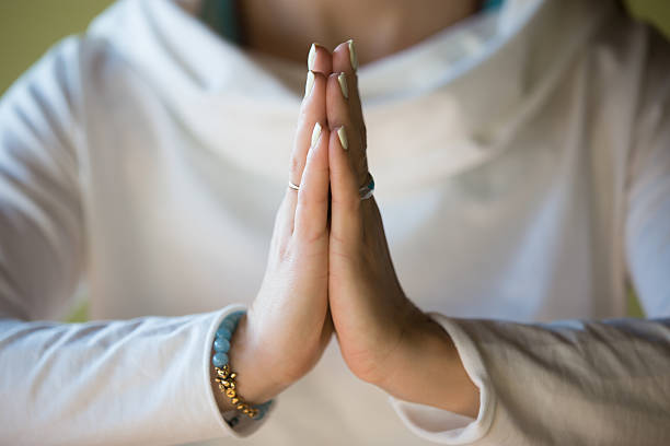 Namaste, close-up Close-up of hands of sporty young beautiful woman in white clothes meditating indoors, focus on arms in Namaste gesture namaste greeting stock pictures, royalty-free photos & images
