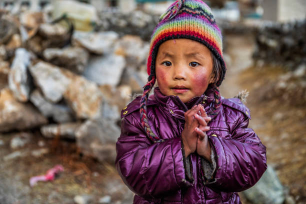 Namaste! Portrait of Tibetan little boy,  Mount Everest National Park, Nepal Tibetan little boy saying namaste, Mount Everest National Park. This is the highest national park in the world, with the entire park located above 3,000 m ( 9,700 ft). This park includes three peaks higher than 8,000 m, including Mt Everest. Therefore, most of the park area is very rugged and steep, with its terrain cut by deep rivers and glaciers. tibetan ethnicity stock pictures, royalty-free photos & images