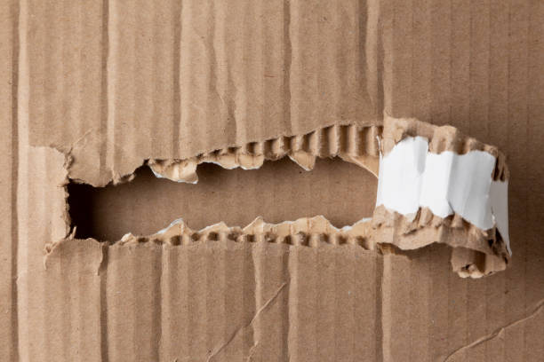 A narrow strip of torn hole in a cardboard box stock photo
