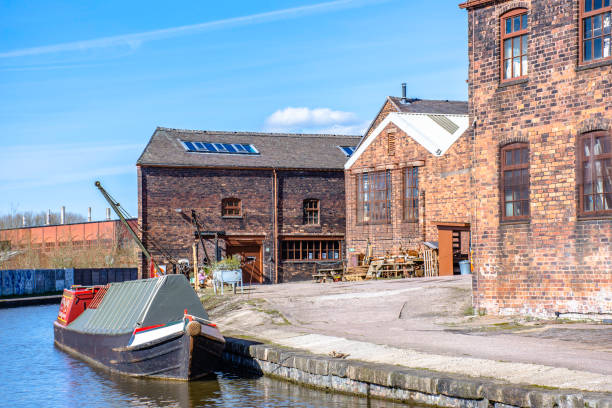 Narrowboat moored nnear old pottery factory on bank of Trent and Mersey canal.19th century historic industrial architecture. stock photo