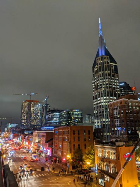Nashville Broadway at Night Rooftop photo of Broadway in downtown Nashville with music bars and clubs on an overcast night with a lot of foot and vehicular traffic. Several skyscrapers, including AT&T Building in the background. broadway nashville stock pictures, royalty-free photos & images