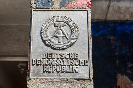 Berlin, Germany - May 28, 2017: The national emblem of the German Democratic Republic or DDR (East Germany) featuring a hammer and a compass, surrounded by a ring of rye on the border post near the Cold War Museum in Berlin.