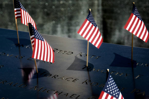 National September 11 Memorial, July 4th, Lower Manhattan, New York City, USA New York City, USA - July 4, 2019: American flags placed at the inscribed names of victims of the 2001 terror attacks, seen at rim of the South Reflecting Pool of the National September 11 Memorial, Ground Zero, World Trade Center, Lower Manhattan, Fourth of July. 911 memorial stock pictures, royalty-free photos & images