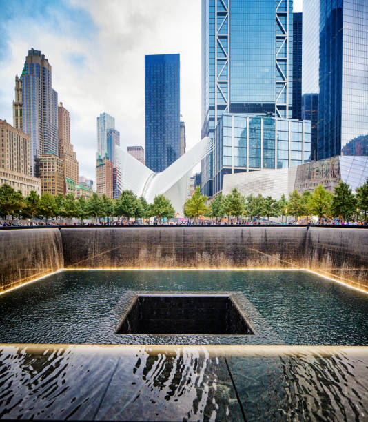 National September 11 memorial waterfalls with Oculus and surrounding buildings National September 11 memorial waterfalls with surrounding buildings on a warm Autumn day 911 memorial stock pictures, royalty-free photos & images