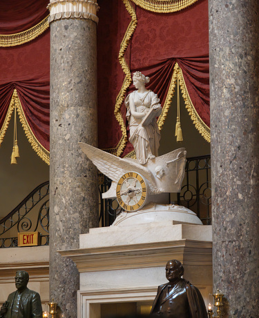 Washington D.C. USA August 7, 2010: National Statuary Hall Clio stands in a winged chariot inside the US Capitol in Washington DC representing the passage of time. The chariot rests on a marble globe on which signs of the Zodiac are carved in relief. The chariot wheel is the face of the clock; its works, installed in 1837, are by Simon Willard.