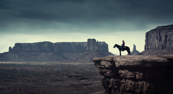 Subject: A native American Indian cowboy riding on a horse over a cliff looking into the stormy distance.