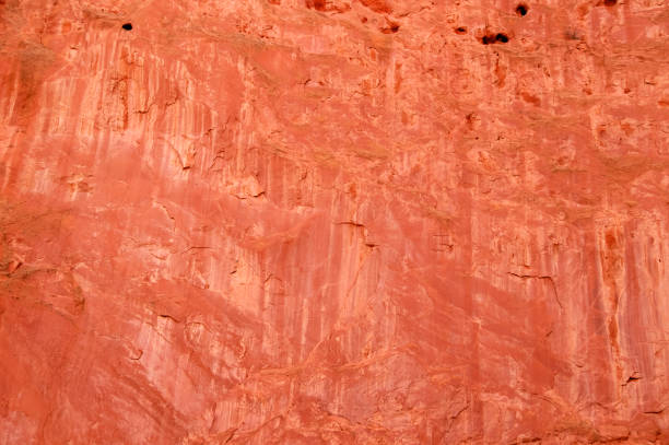 Natural background of a red sandstone bluff with cracks and eroded holes and water washes - beautiful Natural background of a red sandstone bluff with cracks and eroded holes and water washes - beautiful rock face stock pictures, royalty-free photos & images