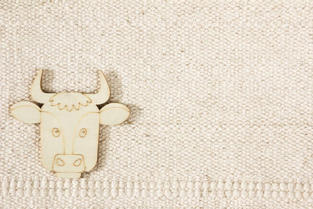 Natural cotton striped uncolored textured sacking burlap background with a wooden figurine of a cow. Farming concept, animal husbandry stock photo