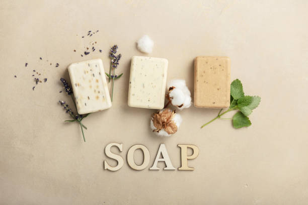 Natural soap bars - lavender, cotton, patchouli - ingredients and wooden letters on natural stone background, flat lay stock photo
