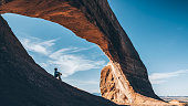 Boy sitting under the Wilson Arch in Utah.