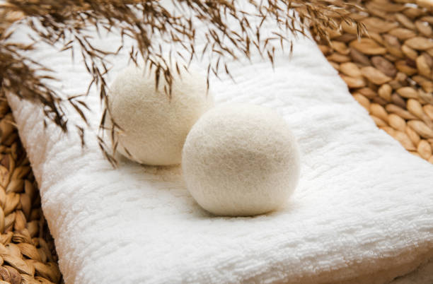 Natural wool dryer balls for more soft clothes while tumble drying in washing machine concept. Earthly tones, reed decoration. Discharge static electricity and shorten drying time, save energy. stock photo