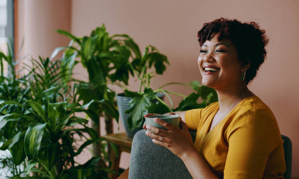 Nature is not a place to visit - it is home Shot of a young woman drinking coffee while relaxing with plants around her at home coffee drink stock pictures, royalty-free photos & images