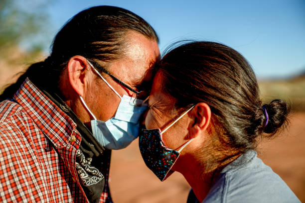 A Navajo Husband And Wife Wearing Masks And Touching Foreheads Breakout in Laughter, Covid19 Shutdown A Navajo husband and wife encourage one another with laughter in spite of the Coronavirus curfew by the Tribal Council in Arizona navajo nation covid stock pictures, royalty-free photos & images