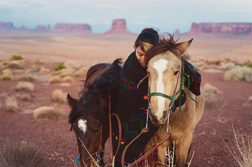 Navajo native american woman hugging her beloved horse at the Arizona desert
