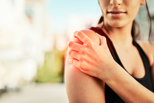 Closeup shot of a sporty young woman holding her shoulder in pain while exercising outdoors