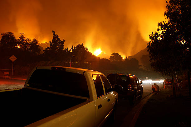 Neighborhood On Fire At Night Residents of a neighborhood sit by and watch a fire threaten their homes. evacuation stock pictures, royalty-free photos & images