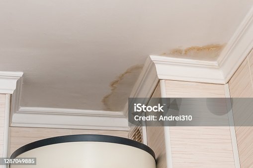 istock Neighbors have a water leak, water-damaged ceiling, close-up of a stain on the ceiling 1287049885
