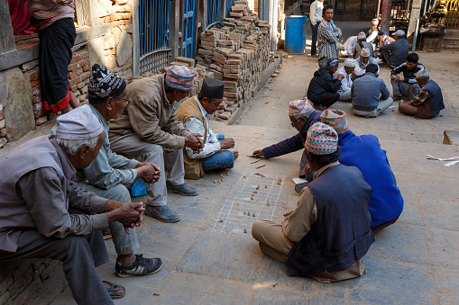 Bhaktapur, Nepal - November 15, 2016: Nepali men playing traditional game in the street. Playing with bamboo sticks and pebbles.