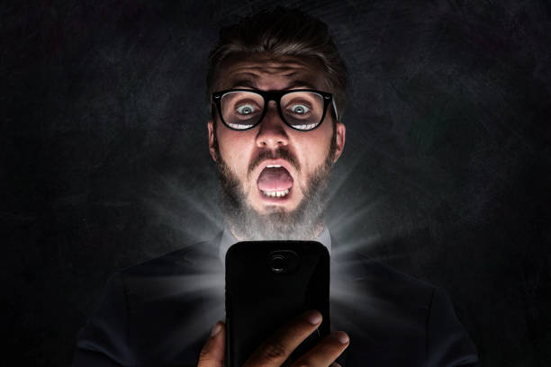 Nerd with glasses is shocked after reading a sms stock photo