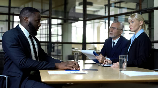 Nervous afro-american man looking at strict employers, career opportunities Nervous afro-american man looking at strict employers, career opportunities prejudice stock pictures, royalty-free photos & images