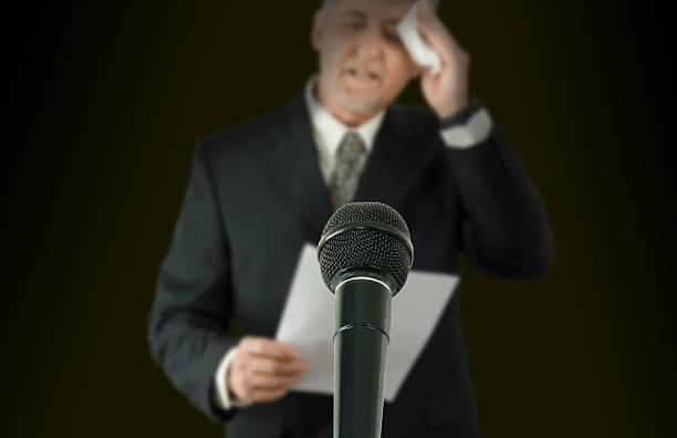 Nervous public speaker or politician wiping brow microphone in focus stock photo