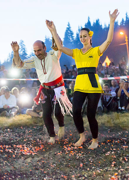 Nestinar woman walking on fire Rijen, Bulgaria - July 18, 2015: A nestinar woman with a child is walking on fire during a nestinarstvo show. The fire ritual involves a barefoot dance on smouldering embers performed by nestinari. firewalking stock pictures, royalty-free photos & images