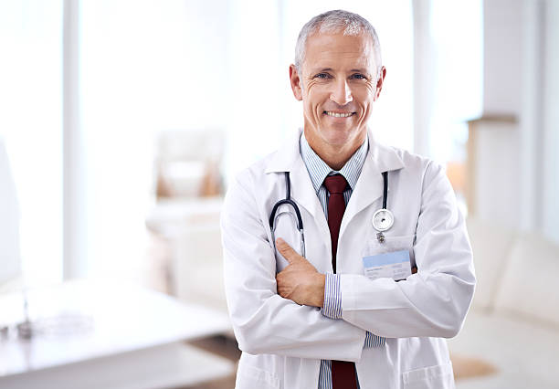 Never fear, the doctor is here Portrait of a mature medical doctor smiling with folded arms males stock pictures, royalty-free photos & images