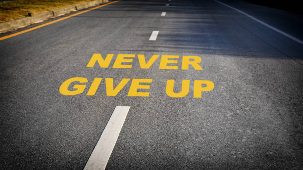 Never give up word on asphalt road surface with marking lines stock photo
