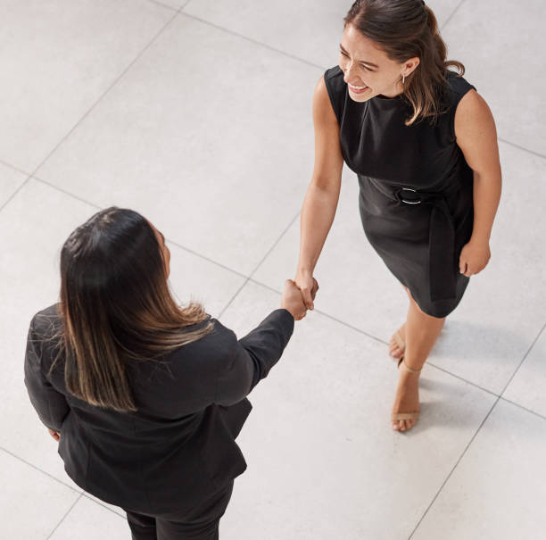 High angle shot of two businesswomen shaking hands in an office