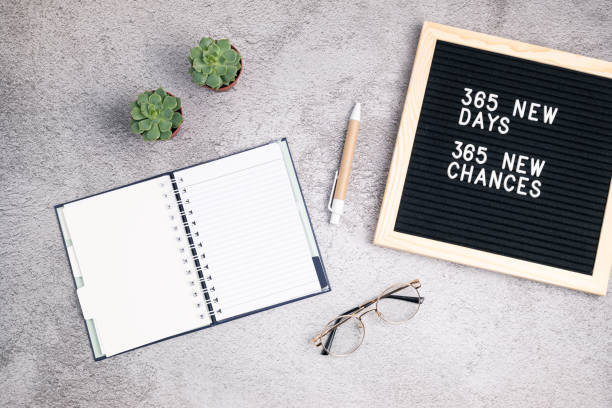 365 new days, 365 new chances. Letter board with motivational quote with notepad , pen, eye glasses and succulent. New yearâs resolutions mockup stock photo