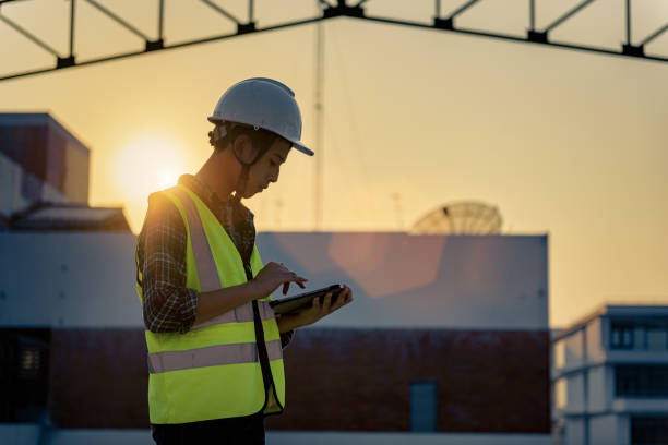 New Engineering teenager people at construction site holding tablet in his hand. Learning in business workflow and Building inspector with BIM technology in construction project while sunset. stock photo