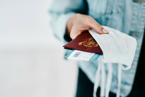 New essentials for a Covid-19 traveller Cropped shot of a woman holding her passport, mask and boarding pass in an airport emigration and immigration stock pictures, royalty-free photos & images