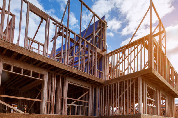 New house under construction framing against a blue sky New house under construction framing beam against a blue sky house   neighborhood  wood stock pictures, royalty-free photos & images