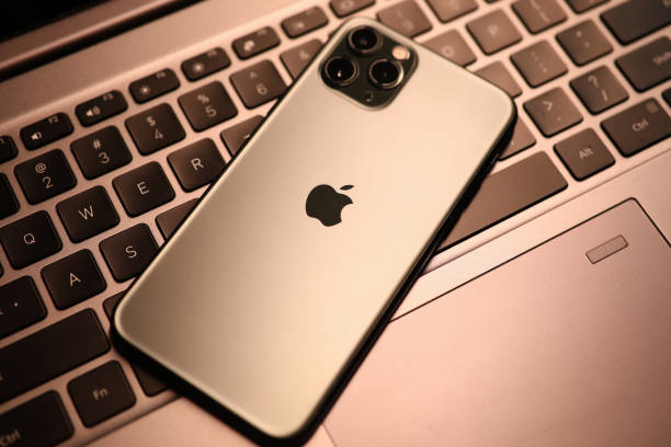 neues modell apple iphone liegt auf laptop-tastatur nahaufnahme - apple computer stock-fotos und bilder