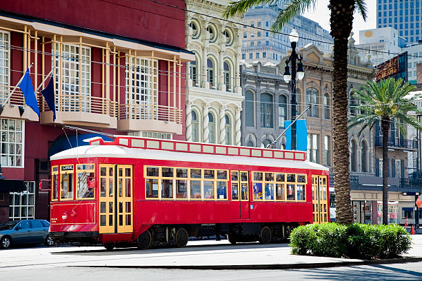 New Orleans Bright Red Streetcar Traveling Amid Palms and Flags New Orleans streetcar traveling down Canal Street. cable car stock pictures, royalty-free photos & images
