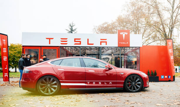 New Tesla Model S showroom parked in front of the red showroom Paris: View from the street of new Tesla Model S showroom parked in front of the showroom with customers admiring the red electric luxury car tesla motors stock pictures, royalty-free photos & images