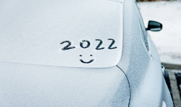 New year 2022 and smiling face written on the rear windshield with snow stock photo
